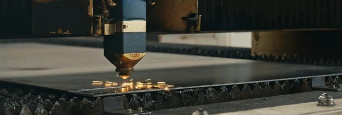 A fibre laser cutting head tracing a part profile through a flat steel sheet